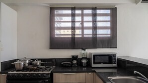 Une cuisine équipée d’une cuisinière, de casseroles, d’un four à micro-ondes et d’un évier.