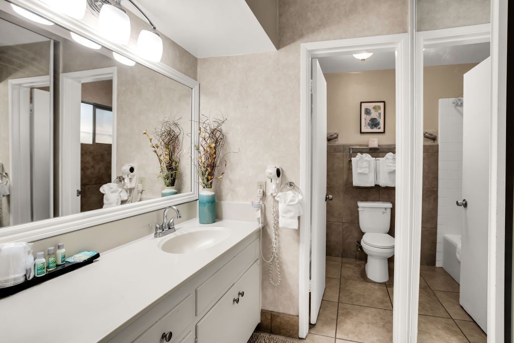 A modern bathroom with a large mirror, white sink, and a toilet.