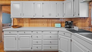 A kitchen with white cabinets, a wooden ceiling, and a countertop with a coffee maker and a toaster. - Quaint 2-bedroom cottage in Houghton Lake - quick walk to lake (Houghton Lake)