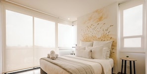 Une chambre moderne avec un grand lit, une vue sur la ville et une Ćuvre dâart accrochĂ©e au mur.