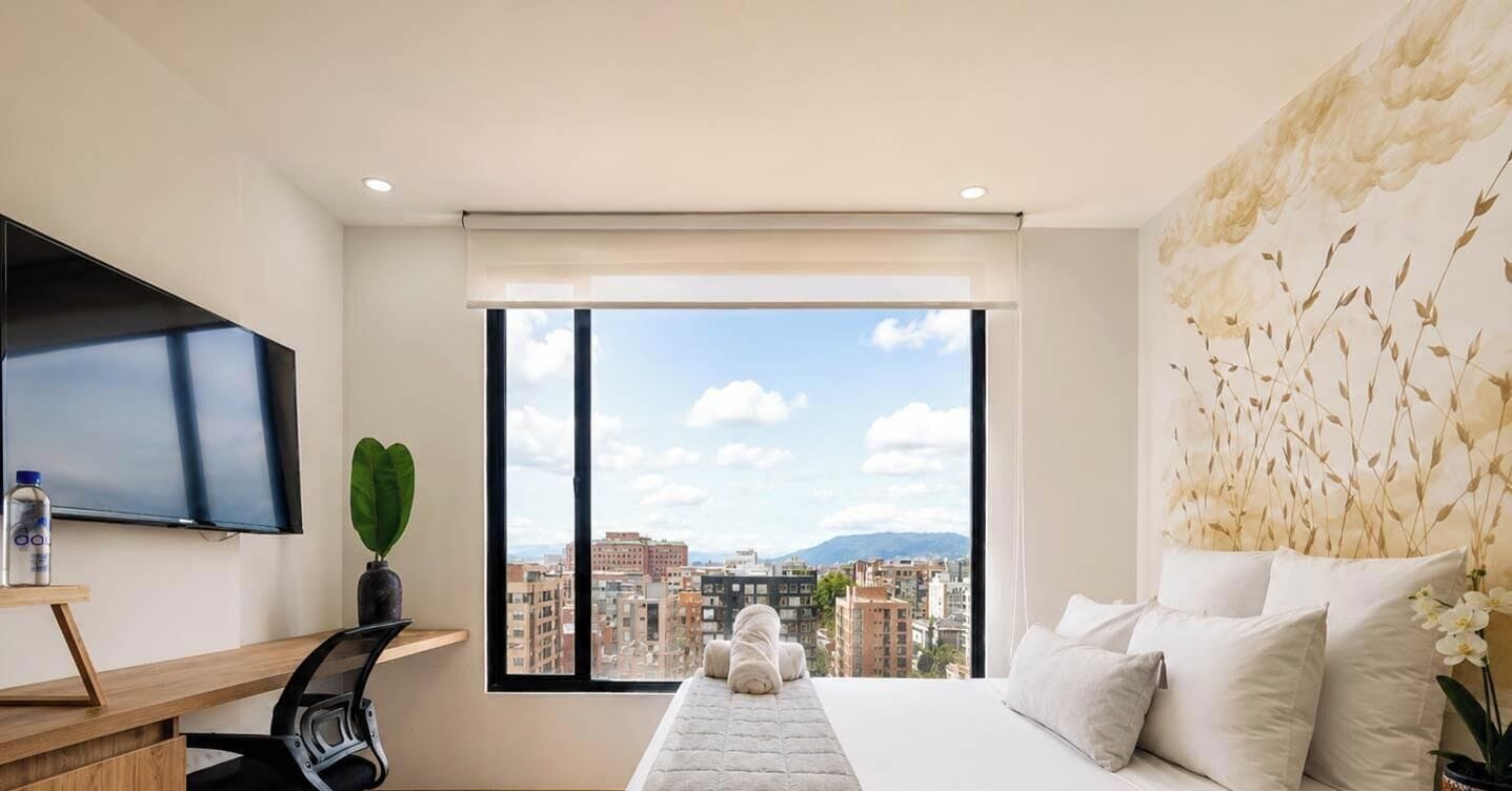 Habitación de hotel moderna con una cama grande, televisión de pantalla plana, escritorio y vista a la ciudad.