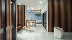 A modern office space with a co-working area, including a sofa, a table with stools, and a unique seating arrangement. - High Park 94 by Jalo (Bogotá)