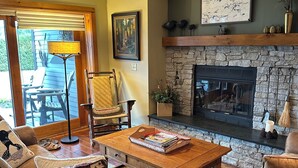 Un salon chaleureux avec une cheminée en pierre, des sièges confortables et un ventilateur de plafond.