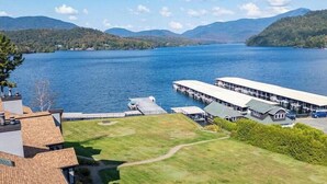 Une propriété au bord du lac, dotée d’un quai, d’une pelouse verdoyante et offrant une vue sur le lac et les montagnes.