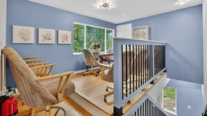 Une pièce avec un mur bleu, une chaise en bois, un bureau et une fenêtre donnant sur un paysage verdoyant.