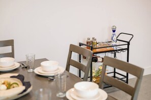 A dining table with plates, glasses, and a metal rack with bottles and a decorative vase. - NEW, fast WI-FI, in unit W/D (San Jose)
