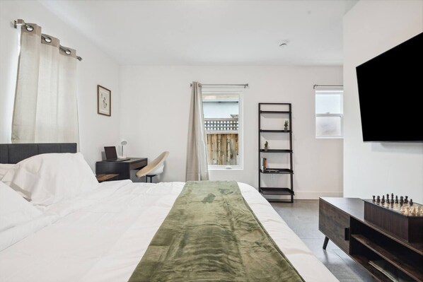 A hotel room with a bed, desk, chair, TV, and a view of the outside. - NEW, fast WI-FI, in unit W/D (San Jose)