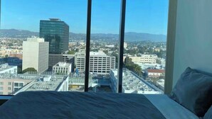 A hotel room with a large bed and a city view through floor-to-ceiling windows. - Ultra Modern 1BD 1BA Flats in heart of LA - true gem (Los Angeles)