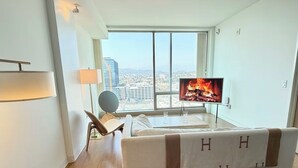 A modern hotel room with a large window, a flat-screen TV, a sofa, a chair, and a table with a lamp. - Ultra Modern 1BD 1BA Flats in heart of LA - true gem (Los Angeles)