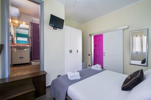 Une chambre d’hôtel équipée d’un lit, d’une télévision, d’une salle de bain avec un lavabo et une douche.