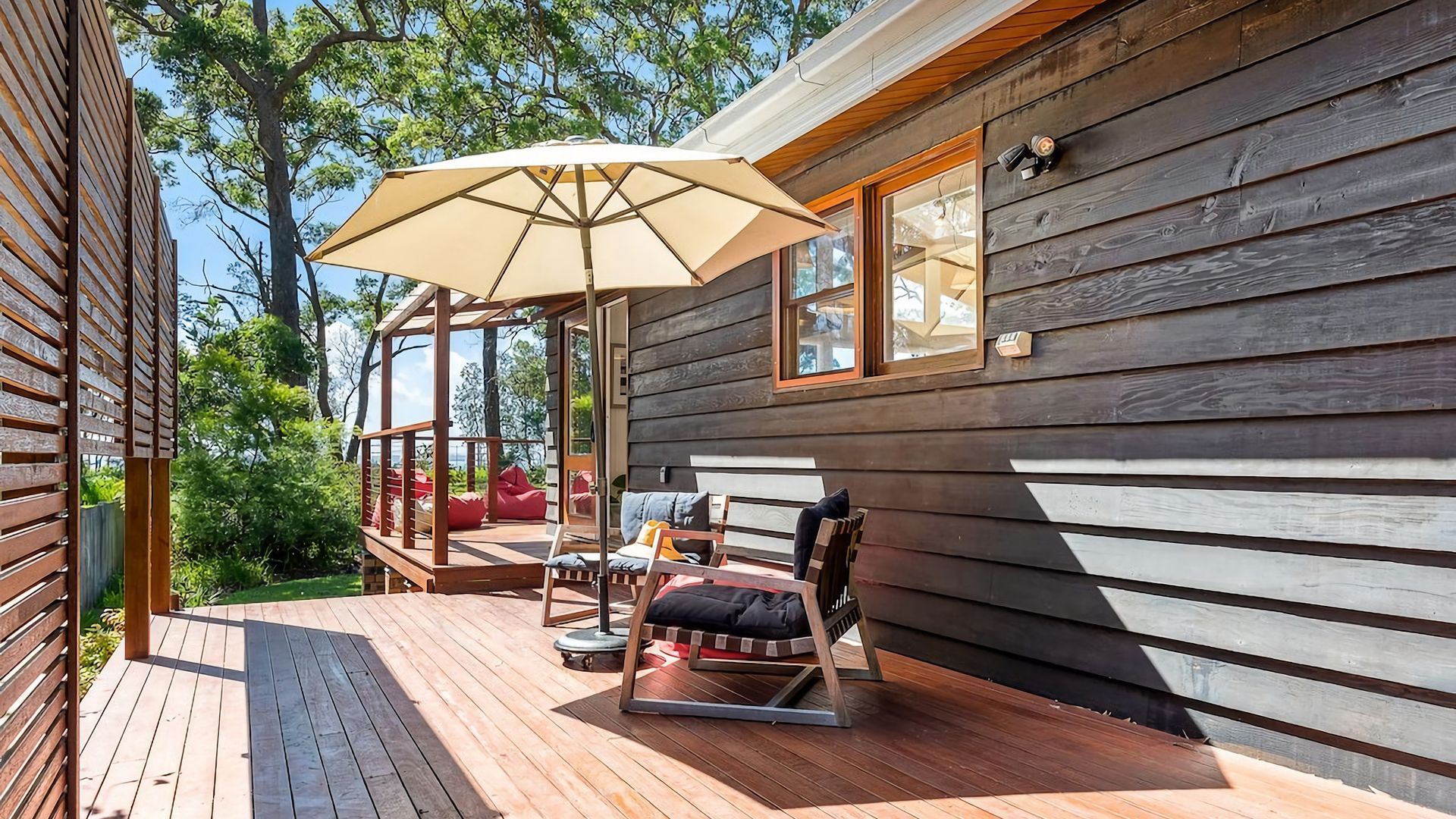 Een houten terras met buitenmeubilair en een grote parasol.