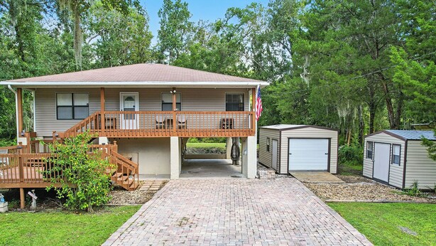 A two-story house with a front porch, a garage, and a small shed. - Charming 1-bedroom condo in cool Crystal River with AC (Crystal River)