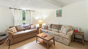 A living room with two sofas, a coffee table, a lamp, and a painting on the wall. - Charming 1-bedroom condo in cool Crystal River with AC (Crystal River)