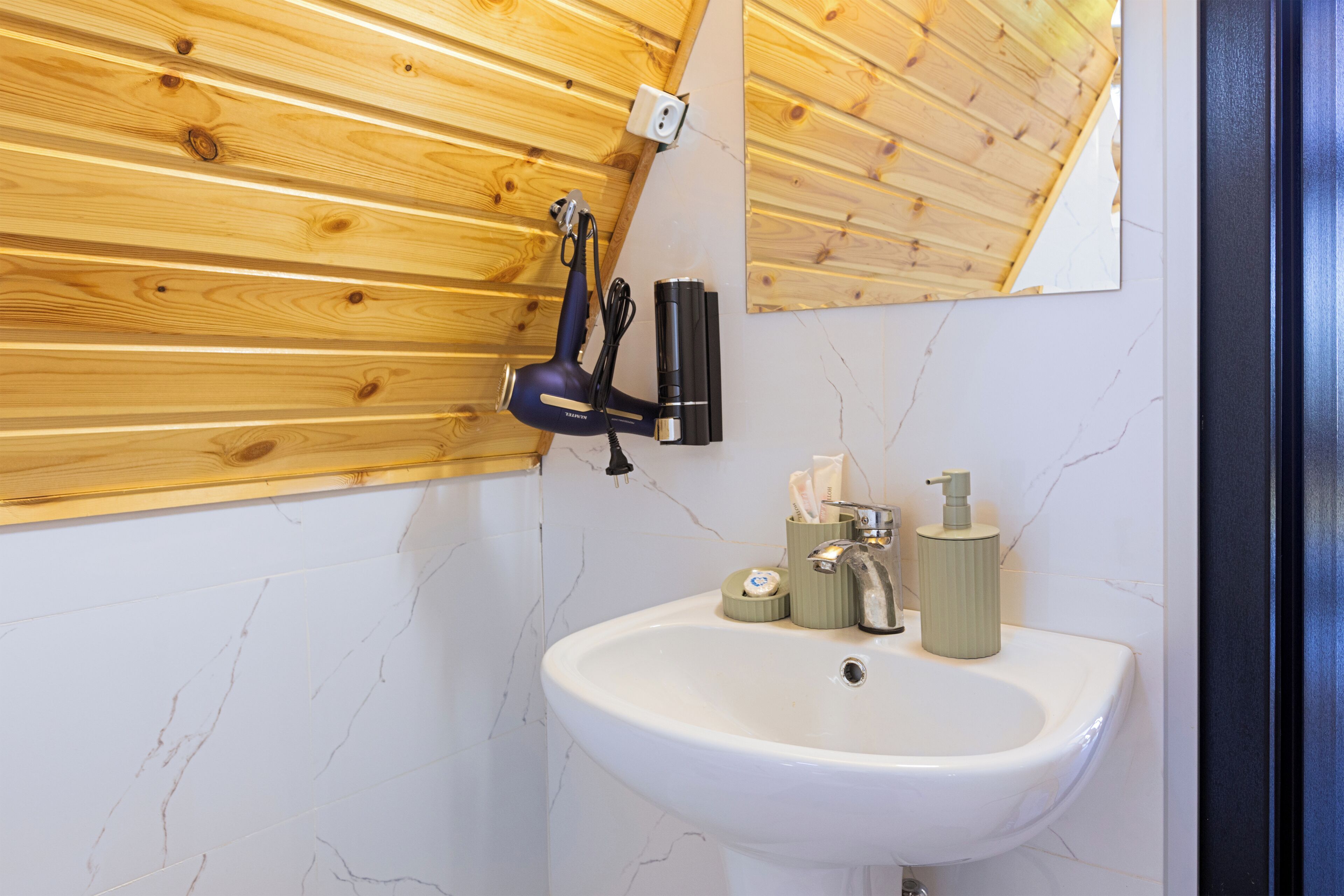 Une salle de bain avec un plafond en bois, un lavabo blanc et un miroir.