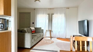 A modern living room with a sofa, coffee table, TV, and curtains. - Cozy  Coastal by Beaches & Redwoods (McKinleyville)