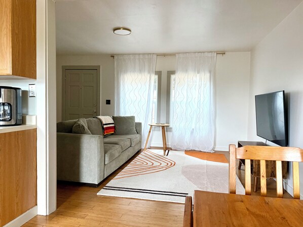 A modern living room with a sofa, coffee table, TV, and curtains.