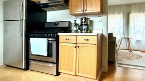 A kitchen with wooden cabinets, stainless steel appliances, and a coffee maker. - Cozy  Coastal by Beaches & Redwoods (McKinleyville)