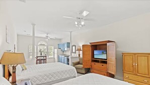 A hotel room with two beds, a TV, wooden cabinets, a desk, and a chair. - Sandy Knees Retreat - Steps to Golf and Minutes to Sunset Beach (Sunset Beach)