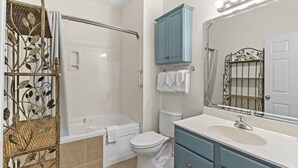 A bathroom with a bathtub, toilet, vanity, and a shower area. - Sandy Knees Retreat - Steps to Golf and Minutes to Sunset Beach (Sunset Beach)