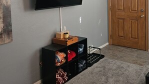 A living room with a flat-screen TV mounted on the wall, a wooden door, and a carpeted floor. - Spacious Family Retreat w/ADA Ramp & ADA bathroom (Maumee)