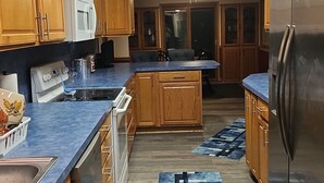 A modern kitchen with wooden cabinets, stainless steel appliances, and a blue patterned rug. - Spacious Family Retreat w/ADA Ramp & ADA bathroom (Maumee)