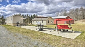 En campingplads med campinghuse, picnicborde, grill og en gyngestativ.