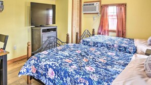 Een kamer met twee bedden, een televisie, een airconditioning en een raam met gordijnen.