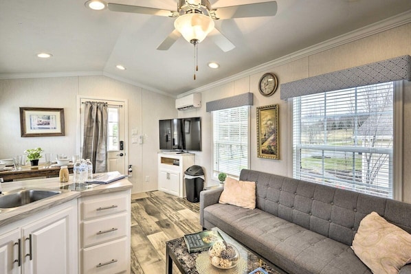 A modern kitchen with a built-in oven, a dining area with a sofa, and a large window with blinds.
