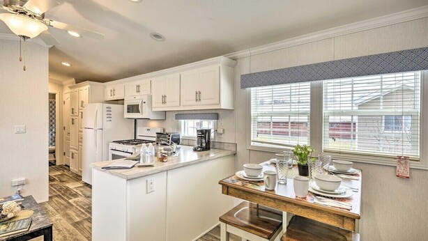 Una cocina moderna con muebles blancos, una isla central y un comedor con mesa de madera.