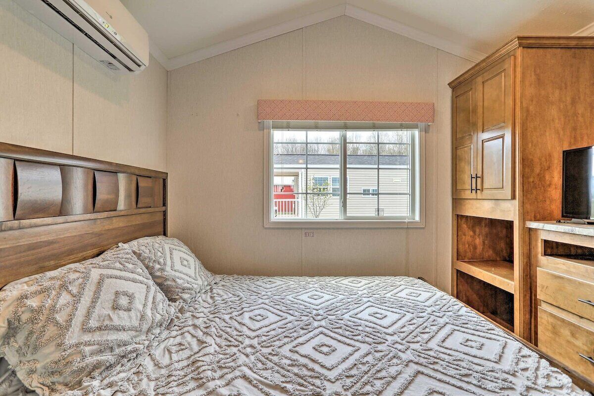 A bedroom with a bed, a window, a TV, and built-in wooden cabinets.