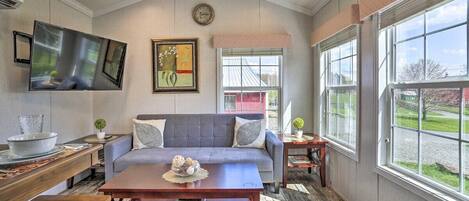 A living room with a sofa, coffee table, and a flat-screen TV mounted on the wall.