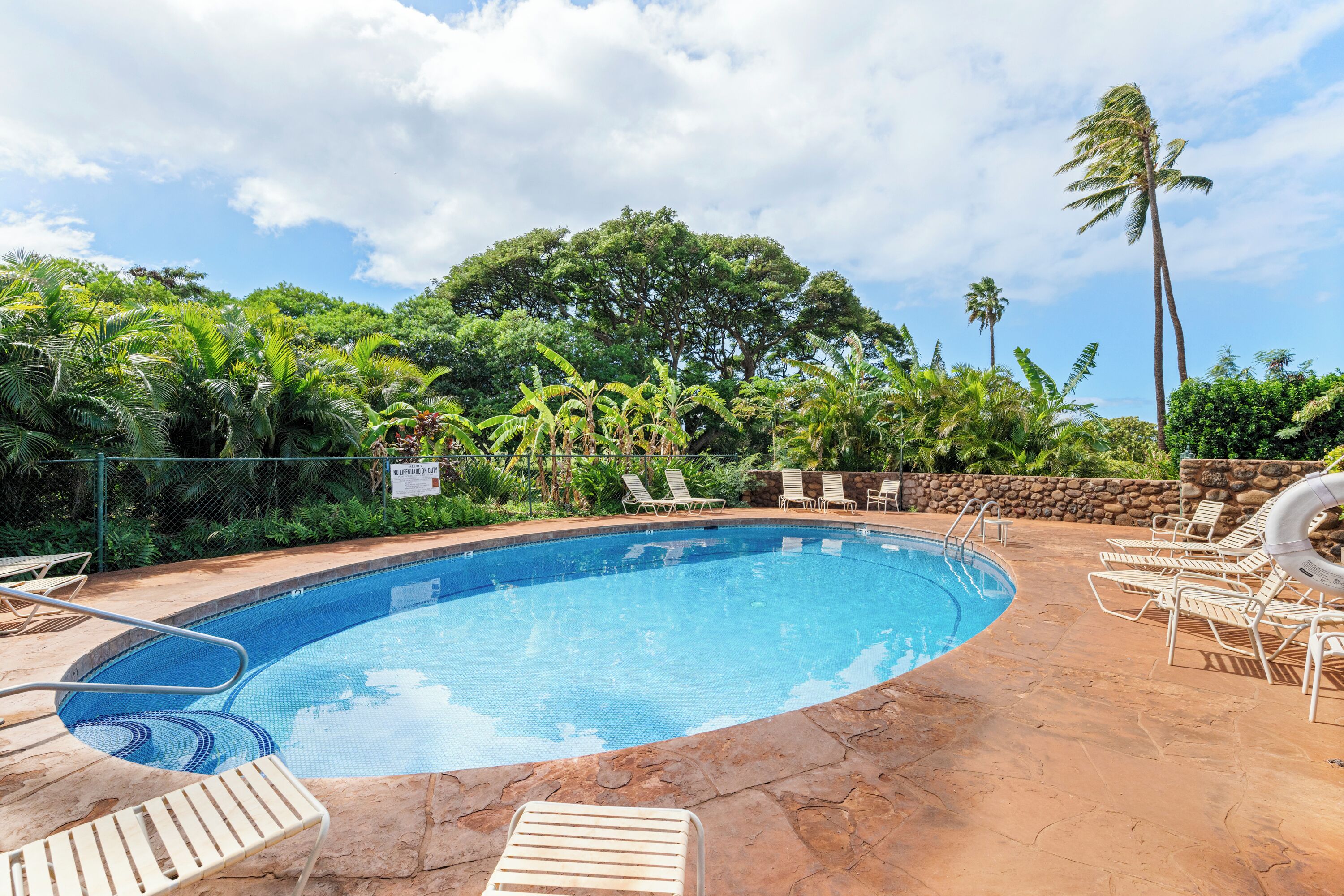 A swimming pool with lounge chairs and a stone deck.
