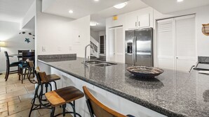A modern kitchen with granite countertops, stainless steel appliances, and a large island with bar stools. - Kaanapali Plantation By Chase N Rainbows (Lahaina)
