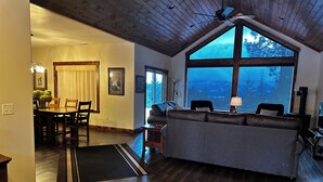 Ein geräumiges Wohnzimmer mit großem Fenster, dunklem Holzboden und einer modernen Couch.