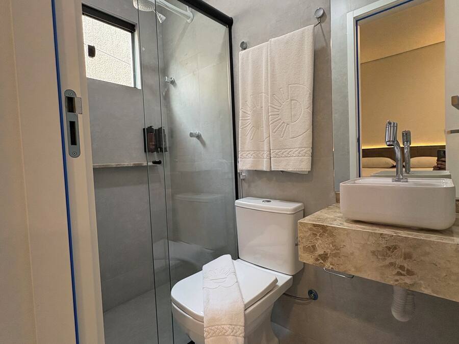 Un baño moderno con cabina de ducha de vidrio, inodoro y lavabo con espejo.