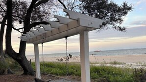 A swing set with a view of the beach and ocean.