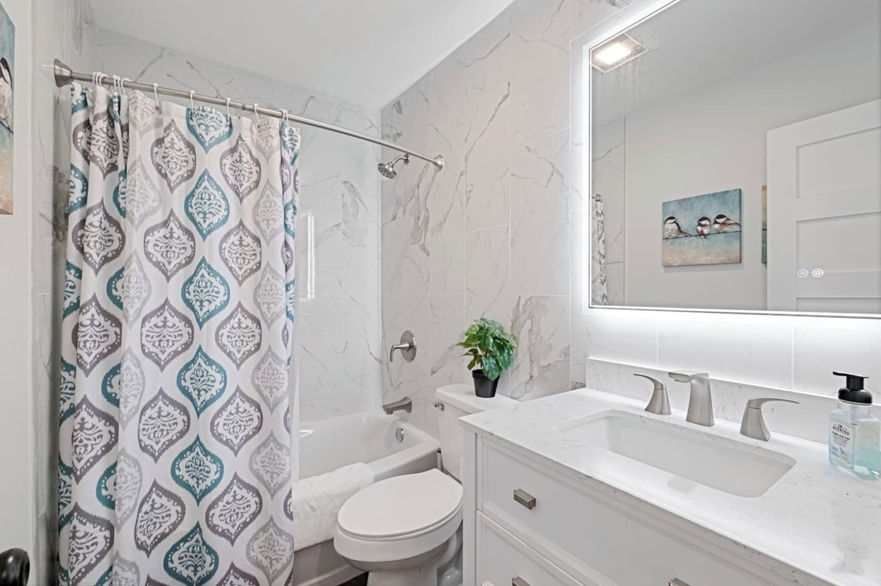 Un baño con cortina de ducha, inodoro, bañera, lavabo y espejo.