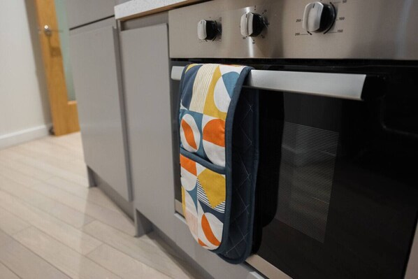 A kitchen with a stainless steel oven and a patterned towel hanging on the oven door. - Luxury Studio Apartment in Liverpool City Centre (Merseyside)