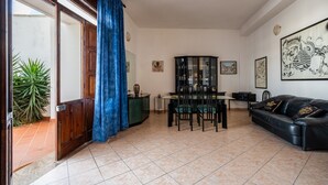 A living room with a dining area, a black leather sofa, and a glass cabinet. - Porto Cesareo apartment 300 meters from the sea (Porto Cesareo)