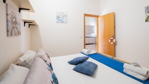 A bedroom with a bed, pillows, a blue mat, a towel rack, and a door leading to a bathroom. - Porto Cesareo apartment 300 meters from the sea (Porto Cesareo)