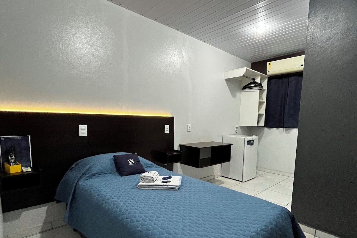 Une chambre d’hôtel avec un lit, un bureau, une chaise et une armoire.
