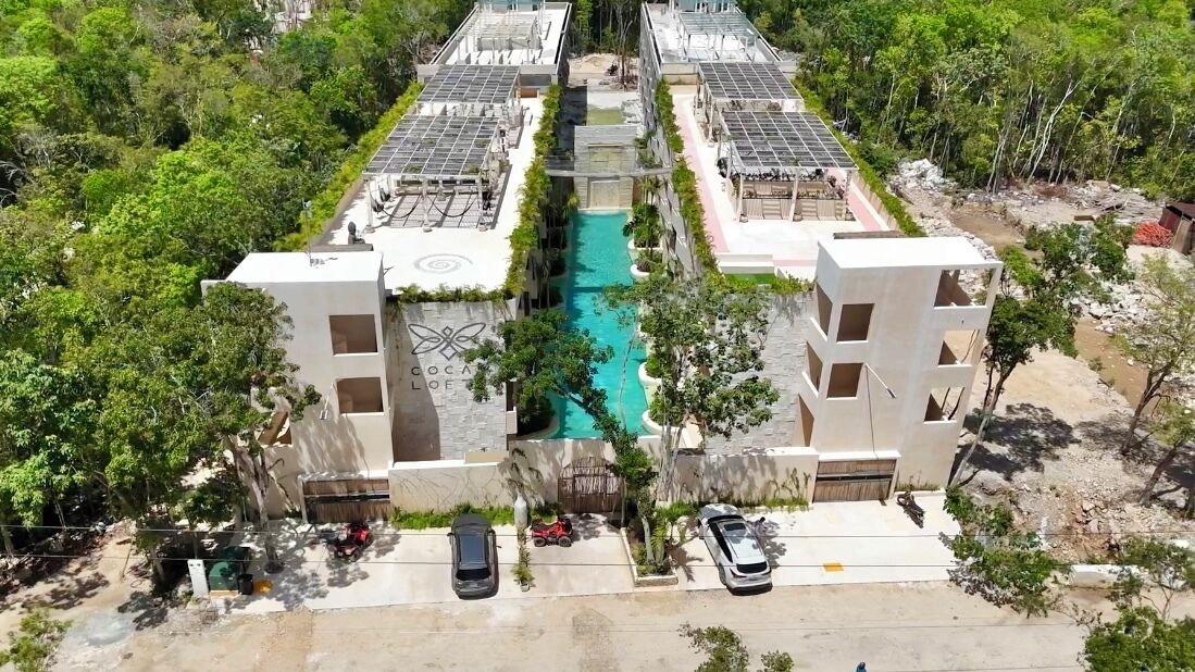 A residential complex with a central swimming pool, surrounded by buildings with solar panels.