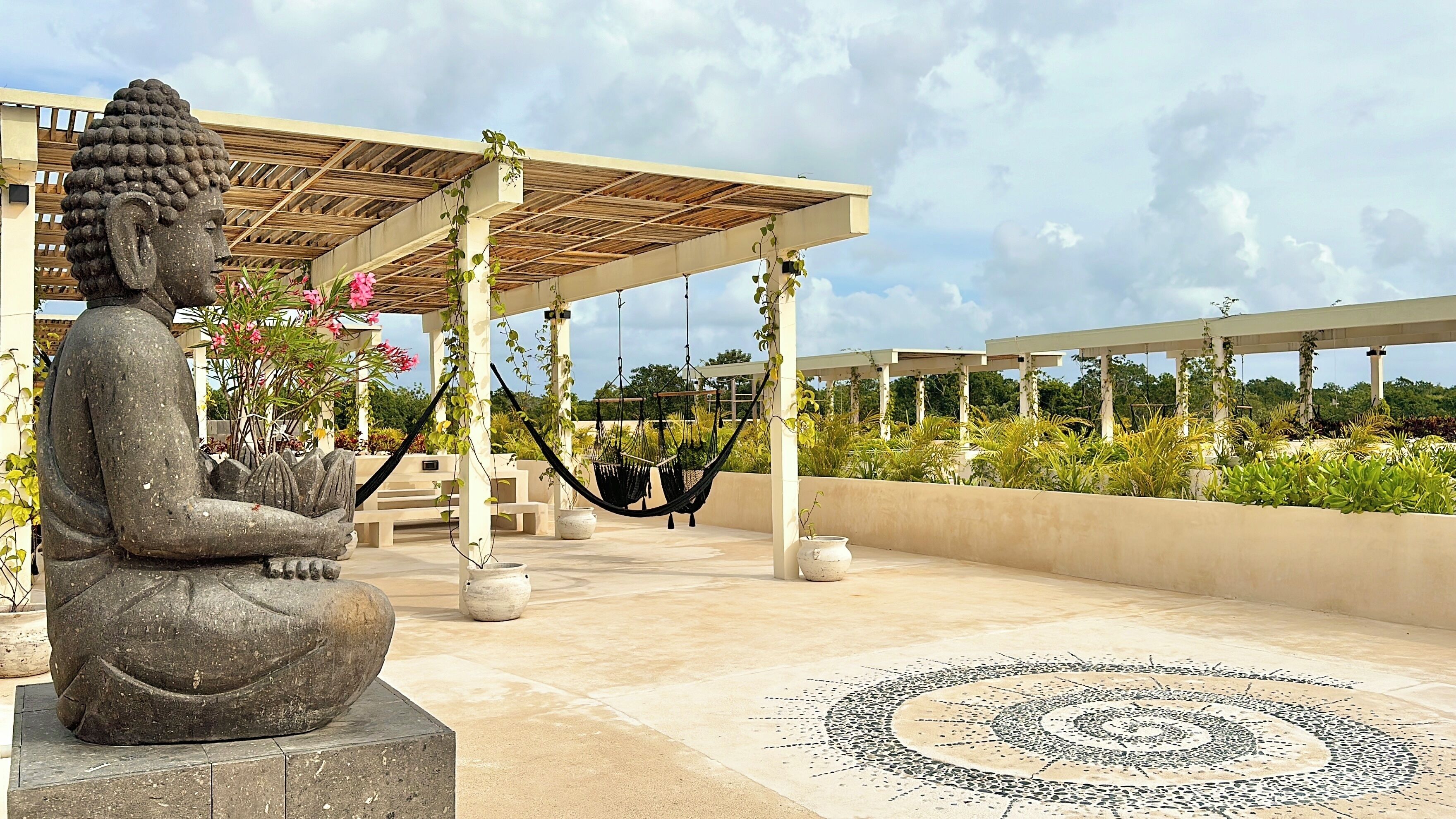 A Buddha statue, a covered seating area, and a sun design on the floor.