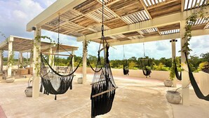 A covered outdoor area with hammocks and potted plants. - COCAY LOFTS BY SANDY POWERFUL (Tulum)