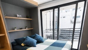Une chambre moderne avec un lit, des étagères intégrées et une vue sur l’extérieur.