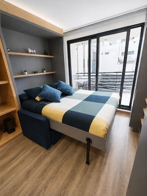 Een moderne slaapkamer met een bed, inbouwplanken en uitzicht op het omliggende landschap.