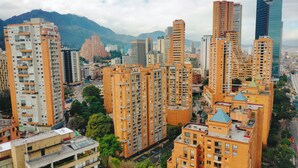 Un ensemble immobilier résidentiel composé de plusieurs immeubles à étages, entouré de verdure et avec des montagnes en arrière-plan.
