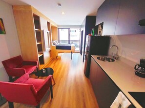 Une cuisine de taille réduite comprenant un évier, une petite table à manger et un canapé.