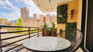 Un balcon avec une table ronde et une chaise, un pot de fleurs et un mur végétal.