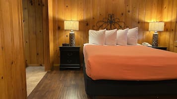 Een kamer met houten lambrisering, een bed, twee nachtkastjes en lampen.